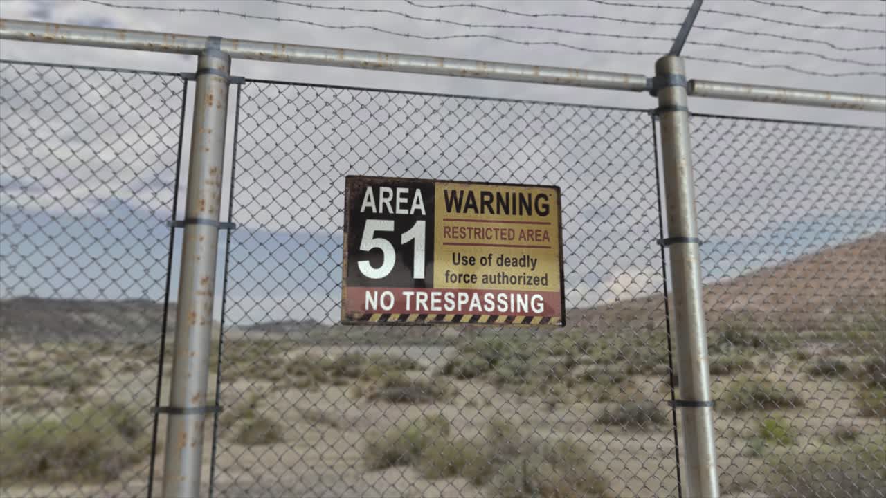 alta calidad 3d cgi render con un plano suave de dollying-out de una valla de enchaines en una instalación militar secreta en una escena del desierto, con un signo de área 51 de advertencia de área restringida