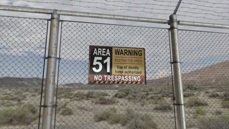 high quality 3d cgi render with a smooth dollying-out shot of a chainlink fence at a secret military installation in a desert scene, with an area 51 warning restricted area sign