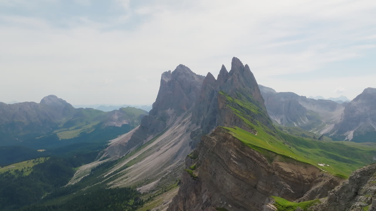 Drone footage of Seceda’s iconic ridgeline in springtime. a sweeping view of dramatic cliffs, rolling pastures, and blossoming alpine terrain in northern Italy