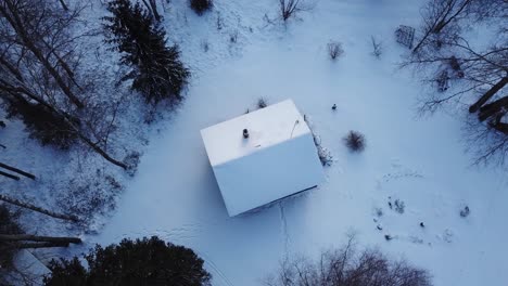 Langsam-Rauchender-Schornstein-Eines-Kleinen-Hauses-Mitten-Im-Wald-Mit-Schneebedecktem-Dach