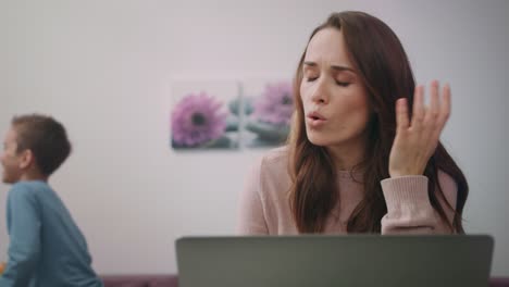 exhausted mom working on laptop. kid distract parent. frustrated mom with child