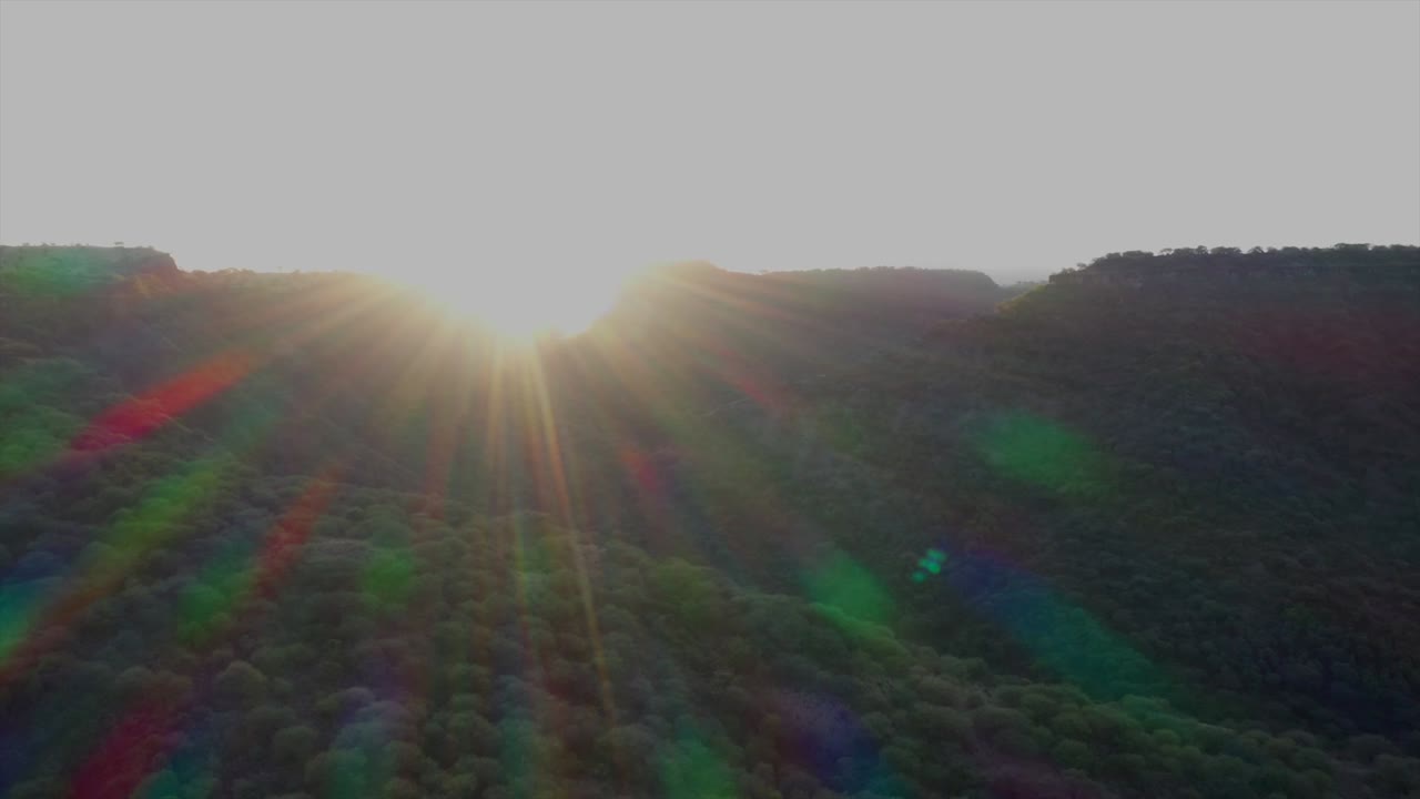 A clip of sunset over a hill with full sunray colors. The rainbow colored sunrays are displayed in slow motion.