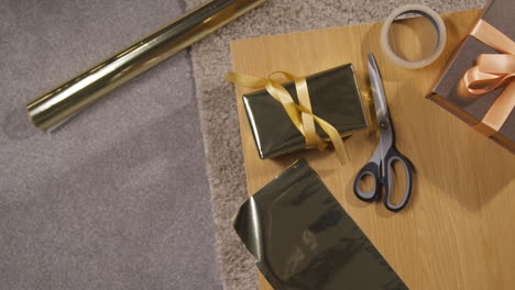 overhead shot of gift or present being wrapped on table at home