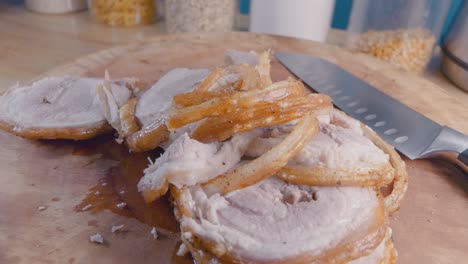 slider shot of sliced belly pork joint with crispy crackling on a wooden cutting board in the kitchen