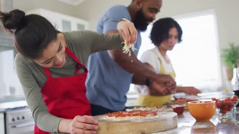 sonriendo diversas amigas y amigos haciendo pizza, cocinando en la cocina, en cámara lenta