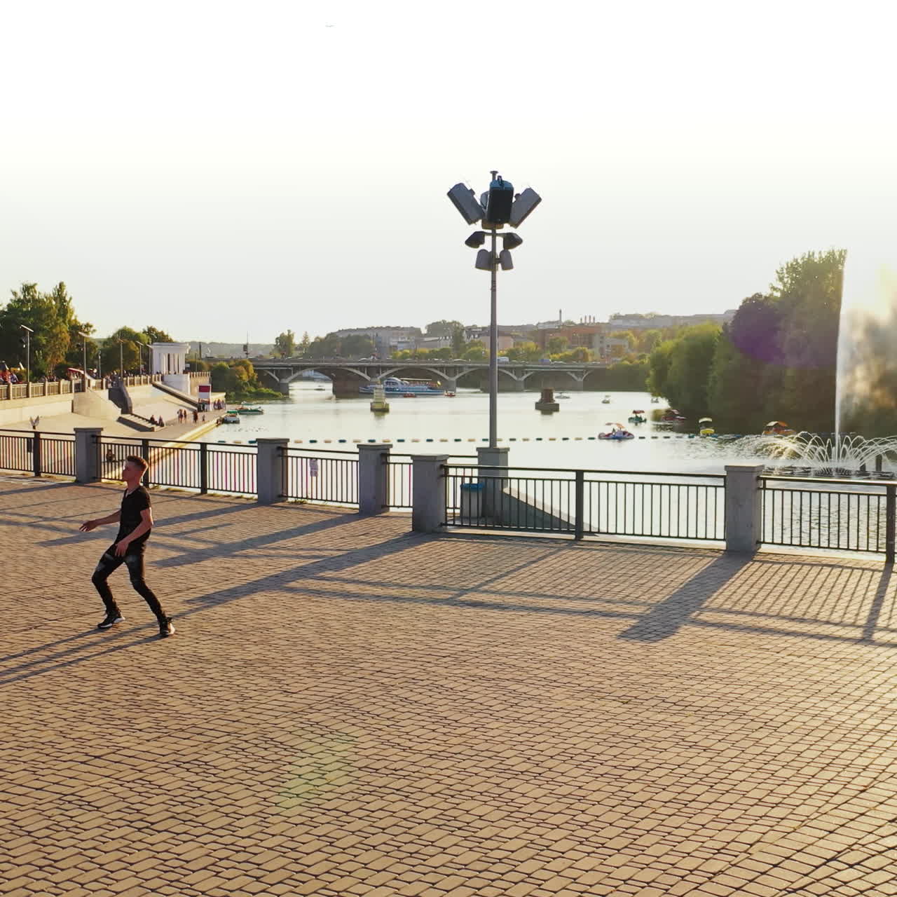 Modern boy dancer is dancing in the street. Urban lifestyle. Hip-hop generation. Boy's emotional moves on the video. Paving stones and young man at fontain background. Aerial view. Young handsome professional dancer boy.