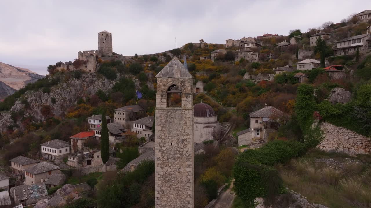 Riprese con drone del villaggio di Počitelj che scende a cascata lungo la verde collina.