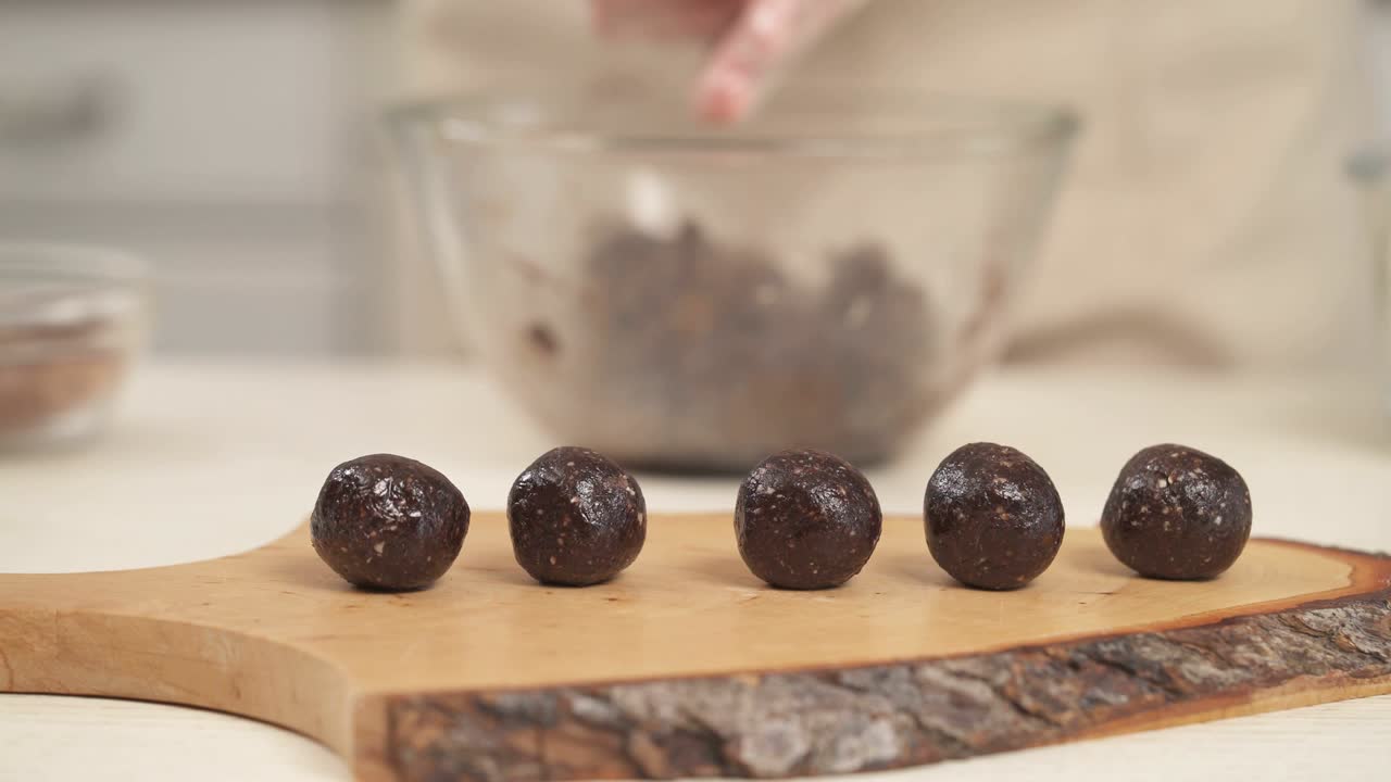 dulces y sabrosos caramelos de chocolate nutritivos colocados en una tabla de cocina de madera en primer plano. mujer haciendo dulces caseros.
