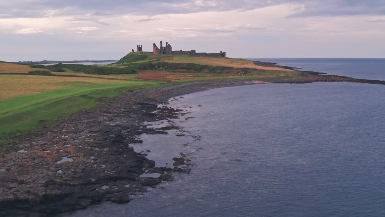 Iconic english Dunstanburgh Castle at sunset, Northumberland, England, UK. Aerial drone view