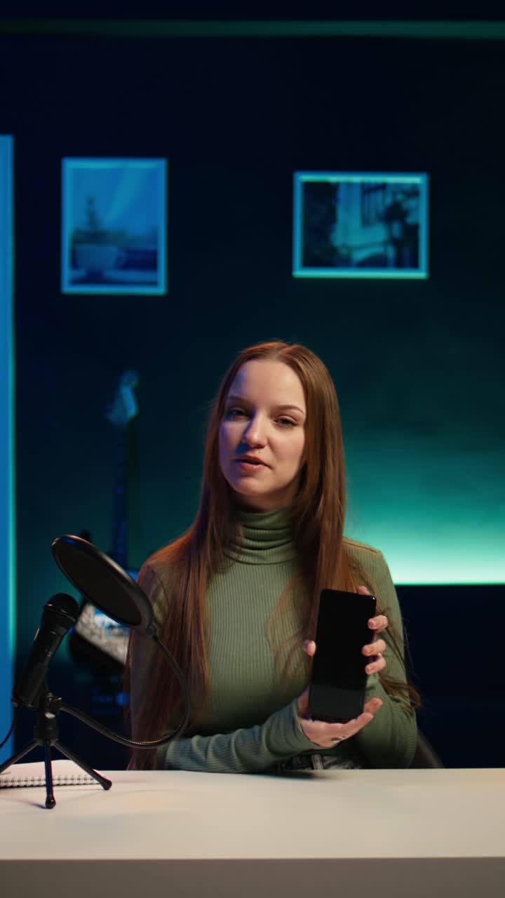 Giovane vlogger che parla e mostra uno smartphone in studio