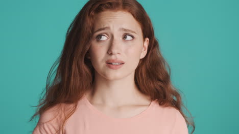 Redheaded-girl-in-front-of-camera-on-turquoise-background.