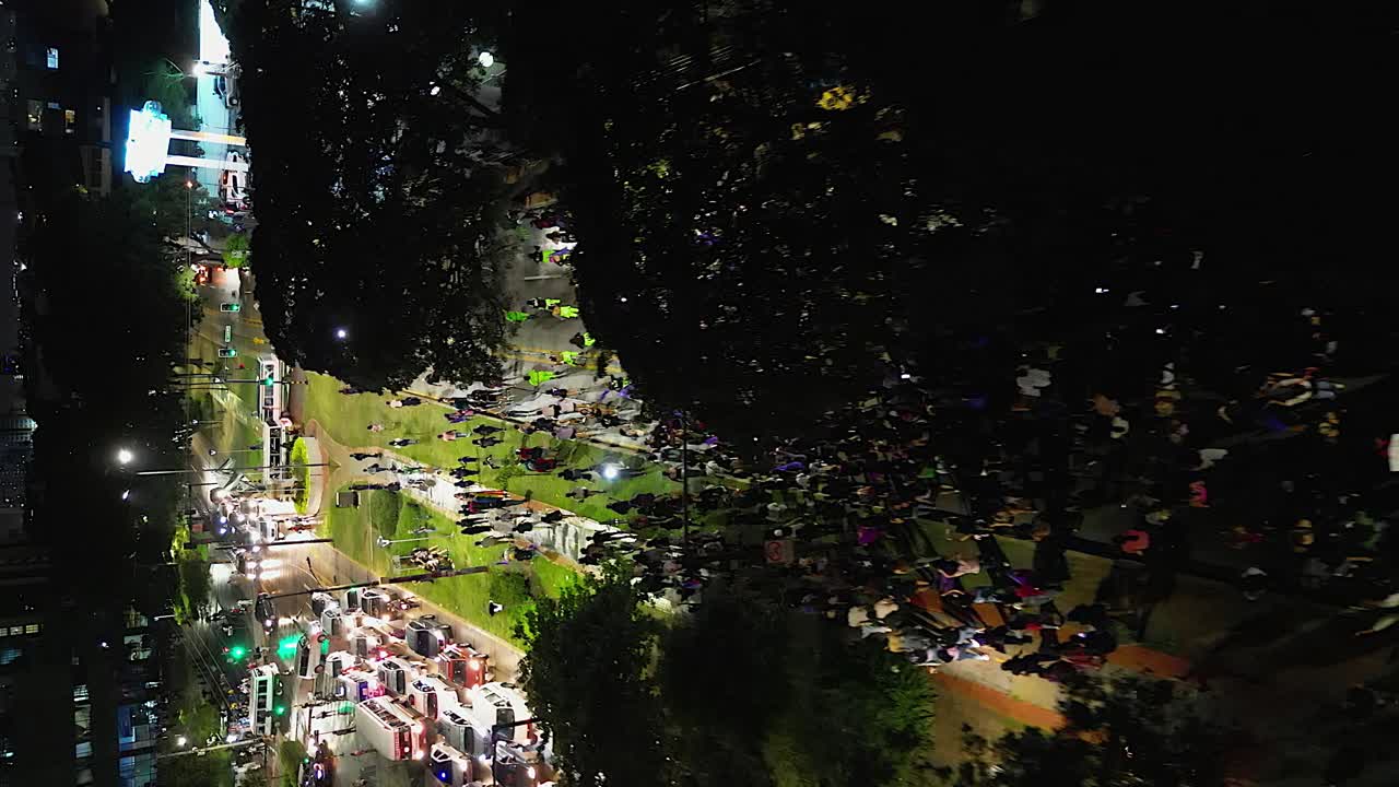 Vertical aerial follows night marchers at Santa Cruz Women's Day event