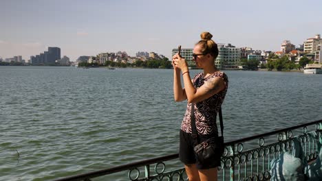mujer joven en el lago tay ho capturando imágenes del paisaje a su alrededor