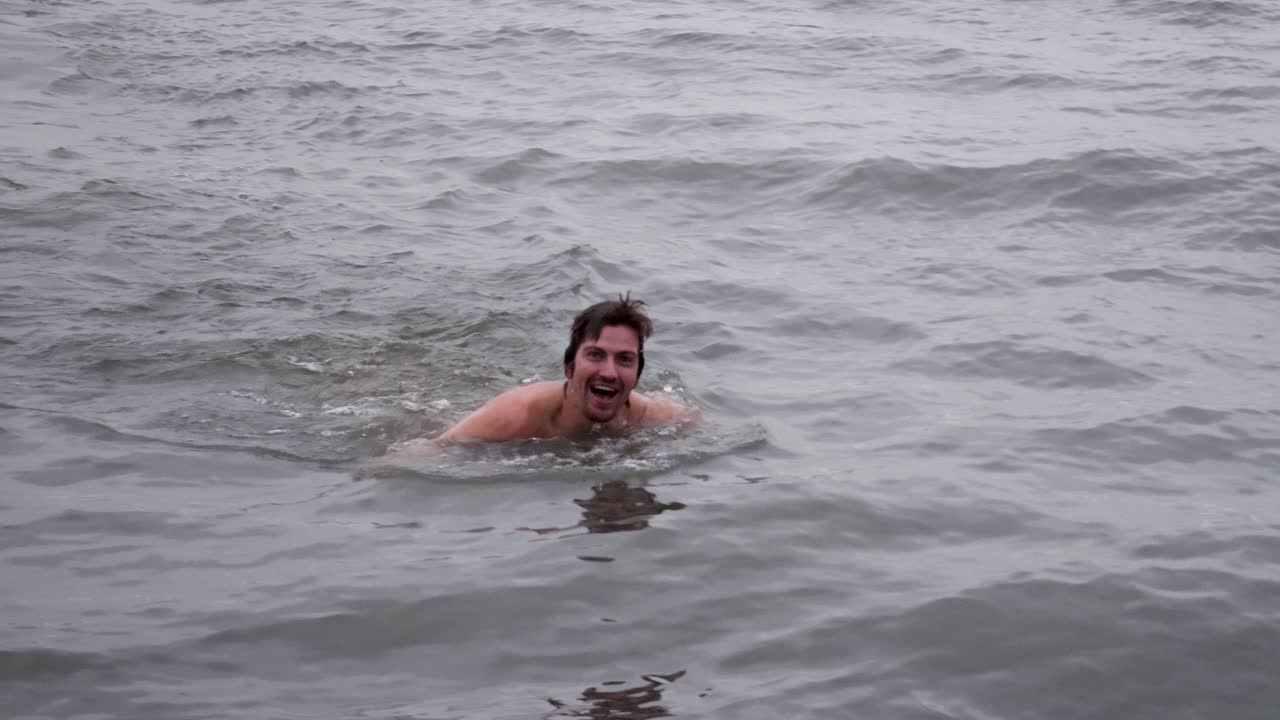 Happy man swimming back to the dock through cold water