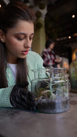 woman caring for succulents in a terrarium