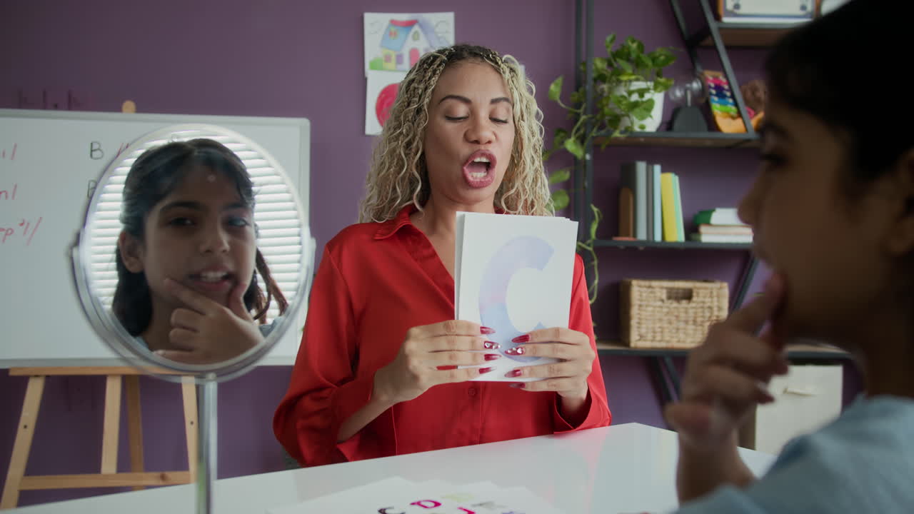 Girl Watching Herself Speak in Mirror during Pronunciation Lesson with Teacher