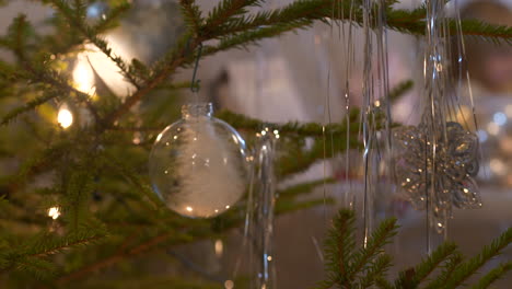 hanging transparent christmas baubles in real christmas tree, close up