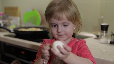 un primer plano de una niña limpiando la cáscara con un huevo de pollo hervido