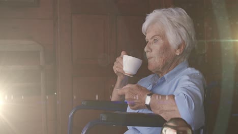 Animation-Von-Leuchtendem-Licht-über-Einer-Ernsthaften-älteren-Frau,-Die-Tee-Trinkt