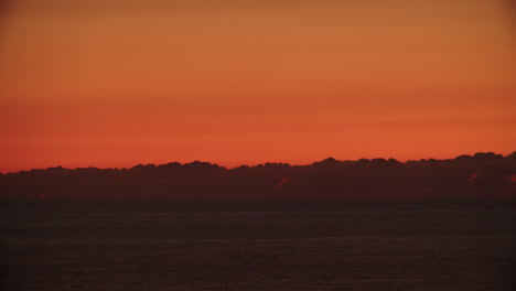 timelapse of amazing orange red sunset at sea with grey clouds above horizon