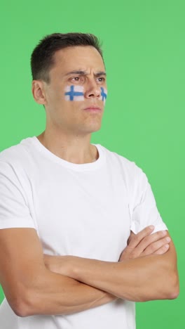 Man with finnish flag painted looking away with serious expression