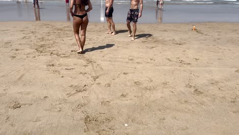 mujer en forma con bikini negro caminando en amarillo en la playa de caparica en portugal