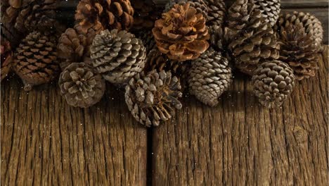 Animation-of-snow-falling-over-pine-cones-on-wood-boards