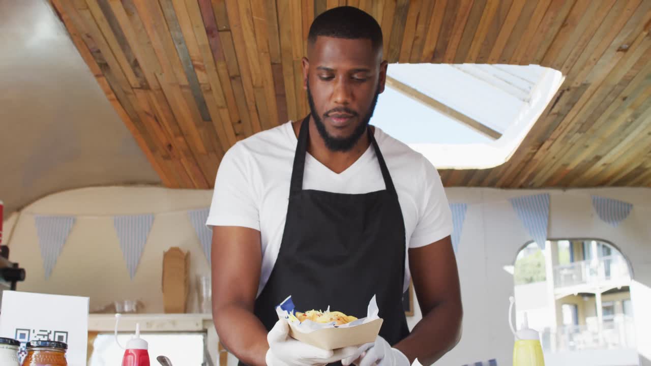 retrato de un hombre afroamericano con un delantal sonriendo mientras sirve comida en un camión de comida