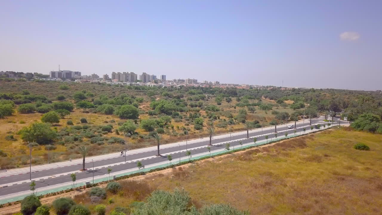 toma aérea de un ciclista en una carretera solitaria en el desierto del sur de israel