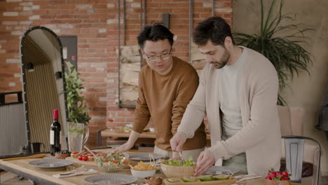 an young man and his friend dressing a salad before a meeting of friends