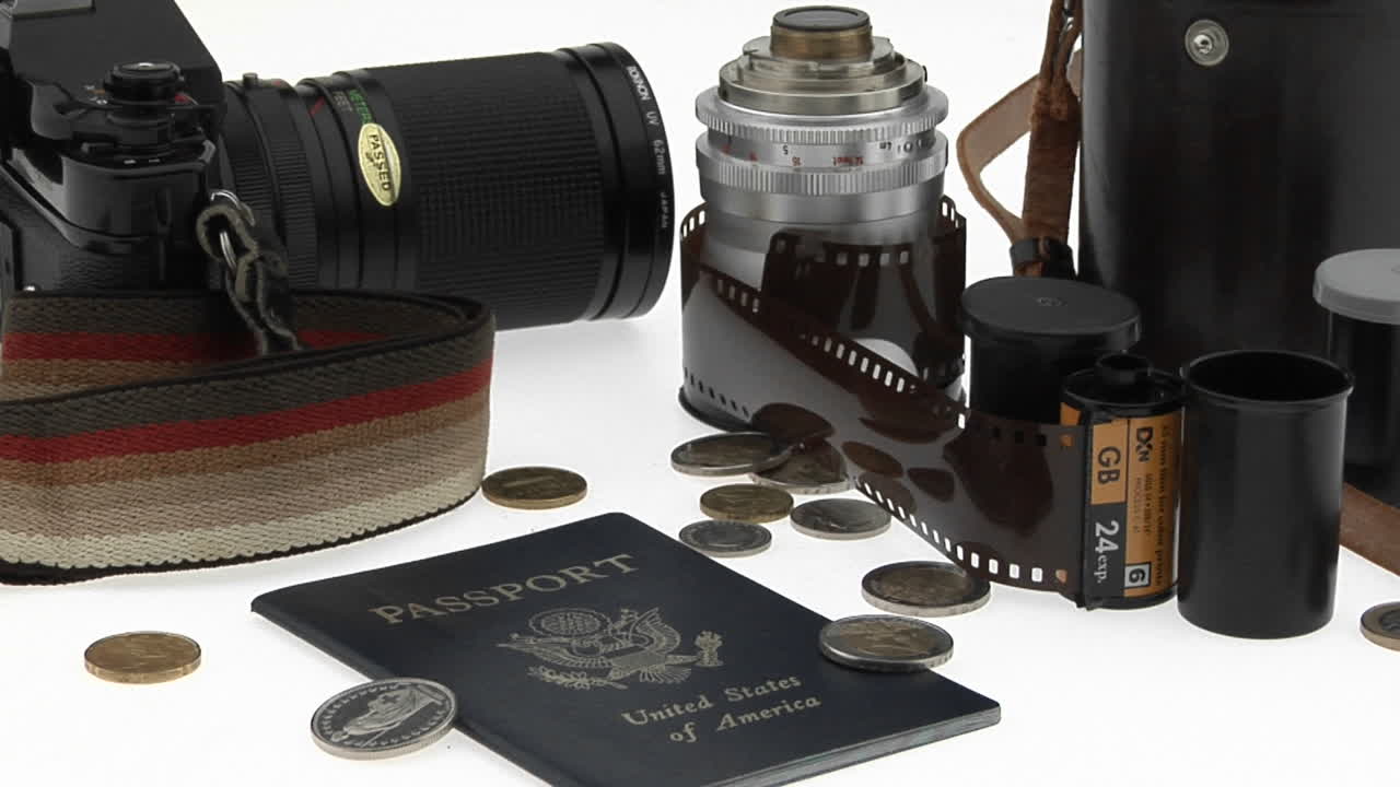 una cámara y equipo de monedas de pasaporte se sientan en una mesa blanca