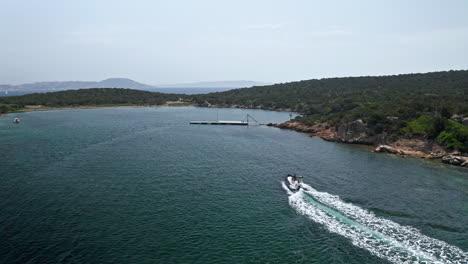 Barco-Navegando-A-Toda-Velocidad-Por-Aguas-Cristalinas-Cerca-De-La-Costa-De-Cerdeña-En-Un-Día-Soleado,-Vista-Aérea