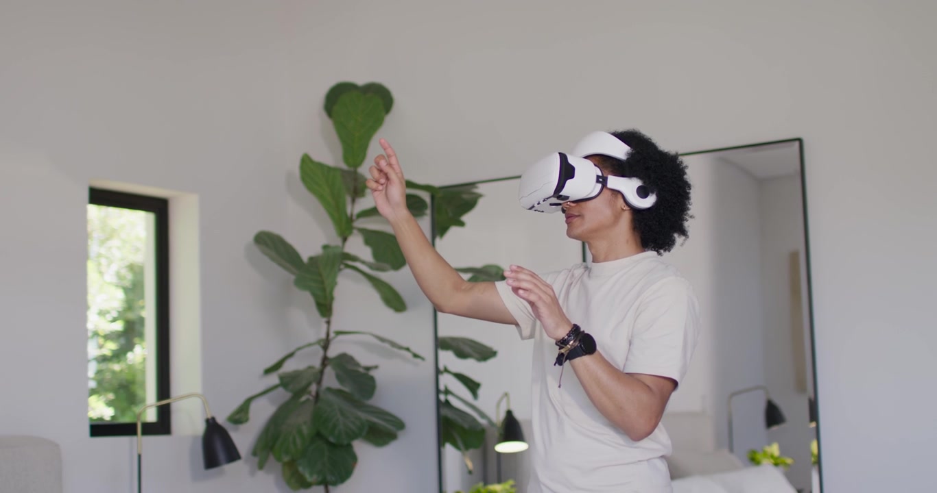 Afroamerikansk man med vitt VR-headset och hörlurar sträcker sig, pekar och väljer hemma.