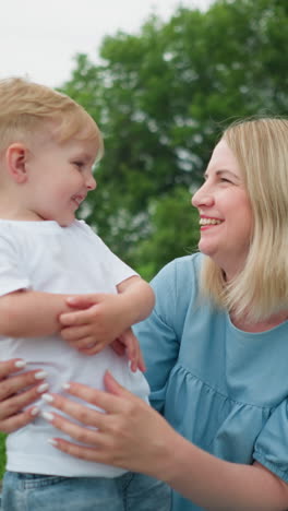 a heartwarming moment of a mother and her young son sharing a joyful conversation outdoors, with a lush green background