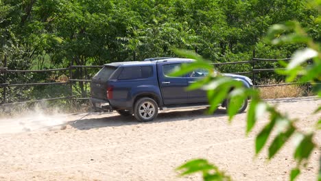 utility car with a drag raises dust while smoothing a track among lush vegetation