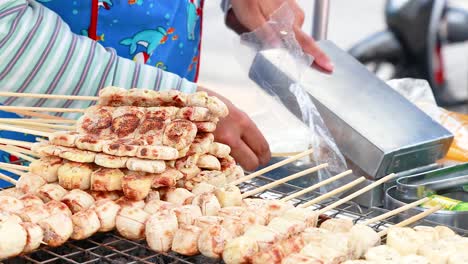 a street vendor grills skewered bananas on a bustling phuket street. bright daylight highlights the vibrant scene and colorful attire