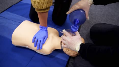 practicing first aid on mannequin. instructor showing how to make chest compressions on dummy during the first aid training indoors