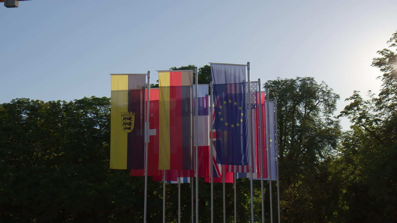 las banderas de los países de la unión europea dispuestas verticalmente contra un telón de fondo de árboles en baden-baden, alemania - toma media
