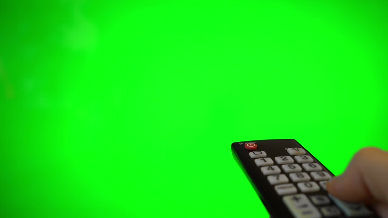 tv 화면을 가리키는 리모컨을 가진 남성 손. 녹색 크로마 키.