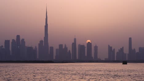 espectacular puesta de sol con la luna detrás del horizonte de dubai con el arroyo de agua salada de dubai en primer plano en dubai, emiratos árabes unidos