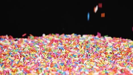 rainbow sprinkles cascade against a black background