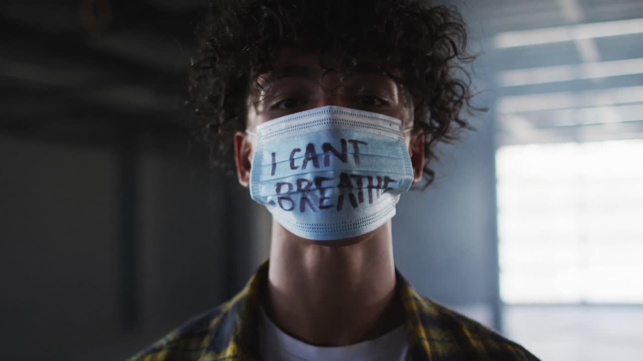 Portrait of mixed race man wearing protest face mask in empty parking garage