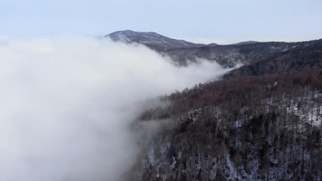 Drohnenansicht-Der-Wunderschönen-Berghänge,-Die-Mit-Schwebenden-Wolken-Bedeckt-Sind,-Im-Wald-Am-Wintertag-In-Kaimaktsalan,-Griechenland