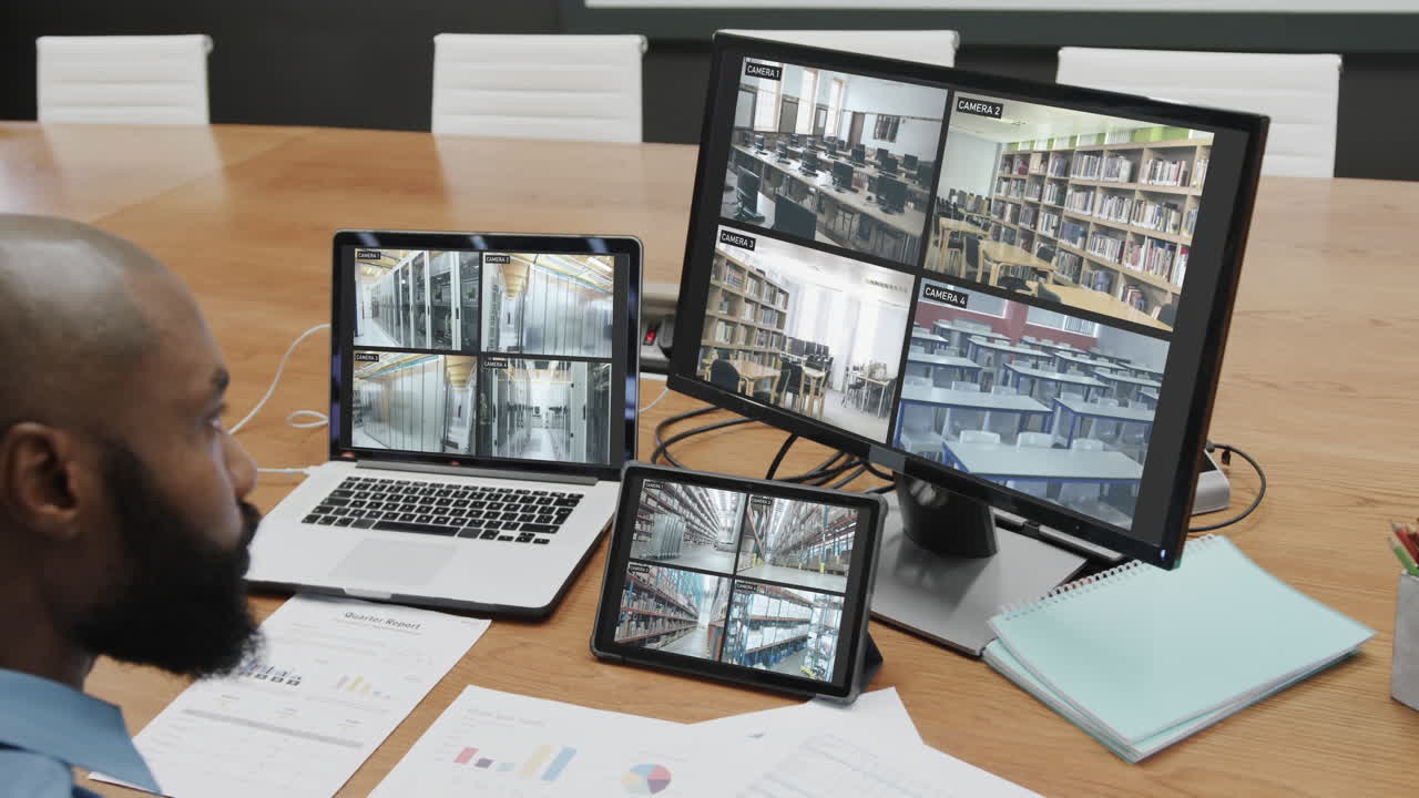 oficial de seguridad afroamericano viendo las vistas de las cámaras de cctv en pantallas de computadora, cámara lenta