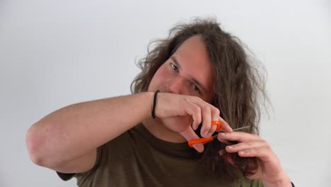 young man getting ready with scissors to cut his own long hair in close up shot with white background