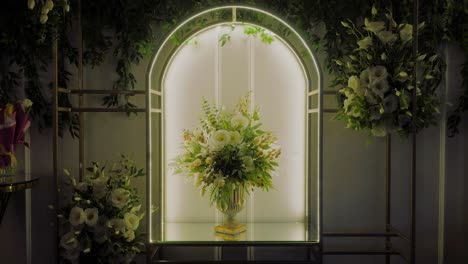 Luxurious-white-flowers-decorations,-arranged-in-a-single-bouquet-in-a-gold-vase-set-within-a-luminous-arcade