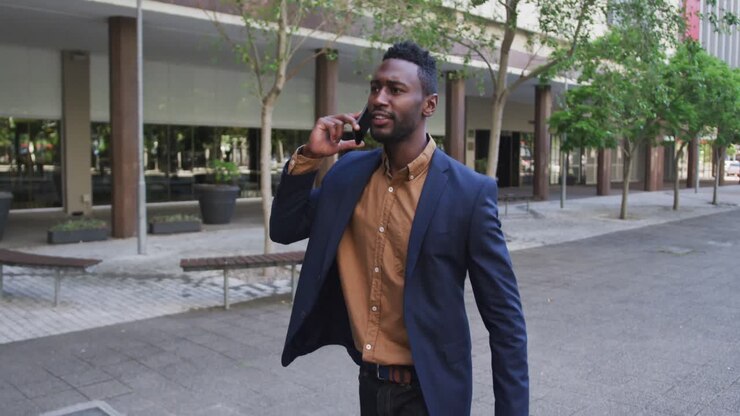 African american businessman using smartphone in city street
