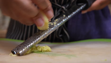 mincing ginger root as an ingredient for a homemade recipe - isolated macro