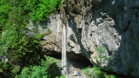 people sitting on the viewing platform, admiring berglistuber waterfall in the canton of glarus in switzerland