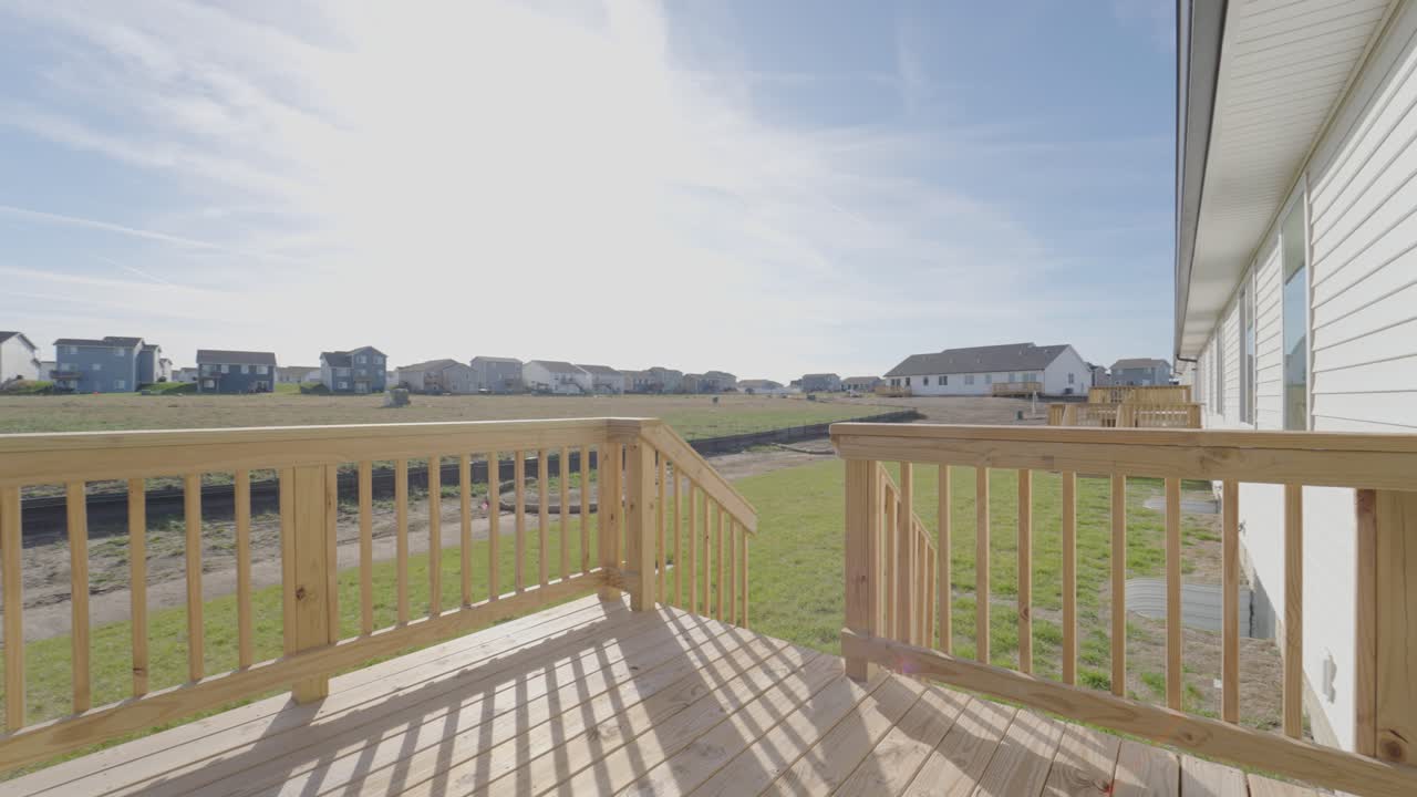 Nybygget hus med standardterrasse, der har udsigt over et nyt boligområde og en majsmark i Iowa